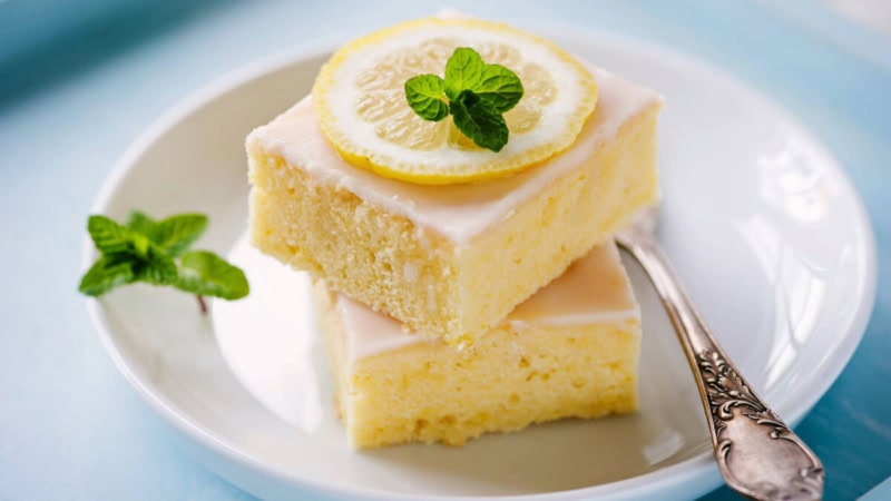 2 Stücke Zitronenkuchen auf einem Teller, mit Minze dekoriert.