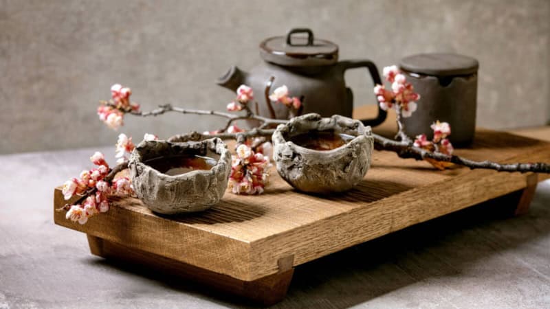 Japanische Kirschblütentee serviert in kleiner traditionellen Teekanne aus Stein.