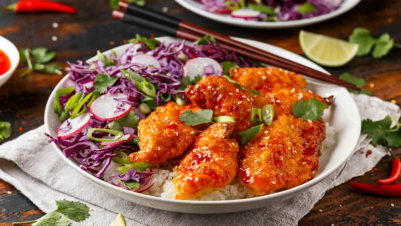 Koreanisches Chicken in einem Schüssel mit Gemüse und Reis.