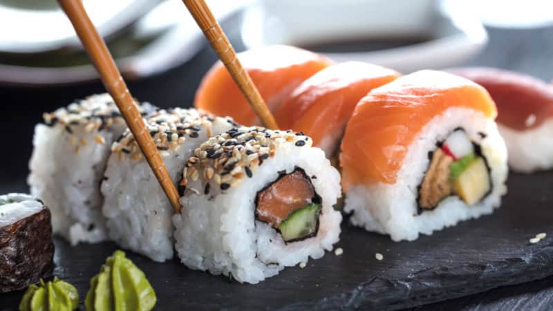 6 Sushi Stücke mit Lachs auf einem Teller.