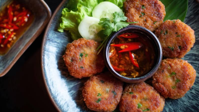 Thailändische Tod Man Pla Speise mit Chilli-Dip und Gemüse auf einem Teller.