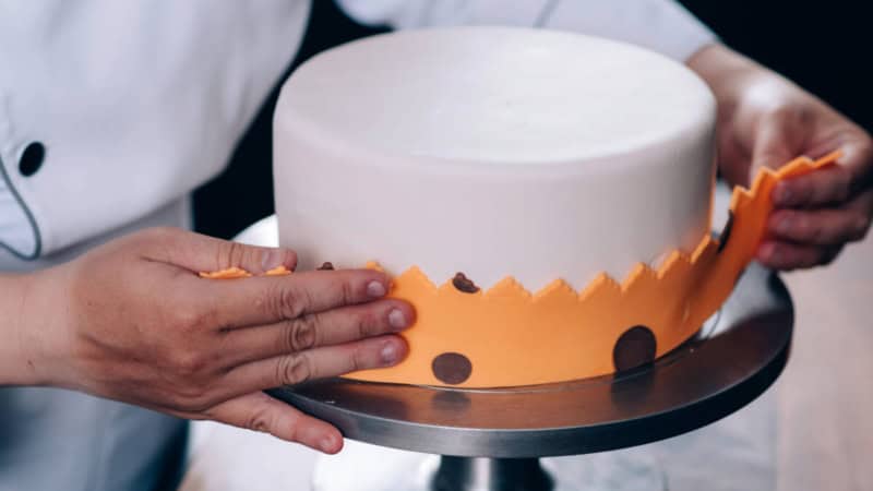 Eine Frau lernt, wie man eine Torte mit Fondanttechnik dekoriert.