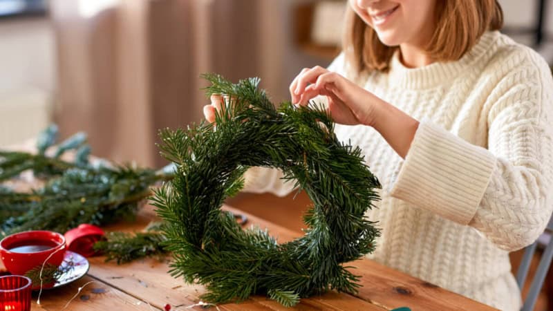 Eine Frau lernt, wie man einen Weihnachtskranz zusammenstellt und dekoriert.