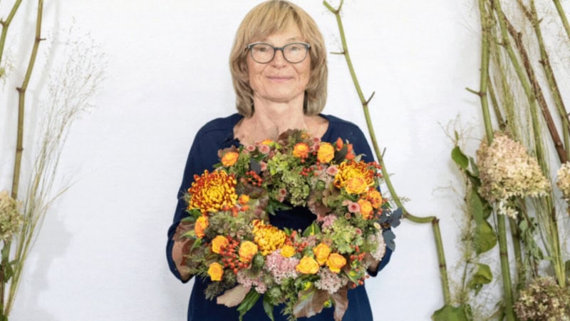 Eine Frau zeigt ihren selbstgemachten Blumenkranz.