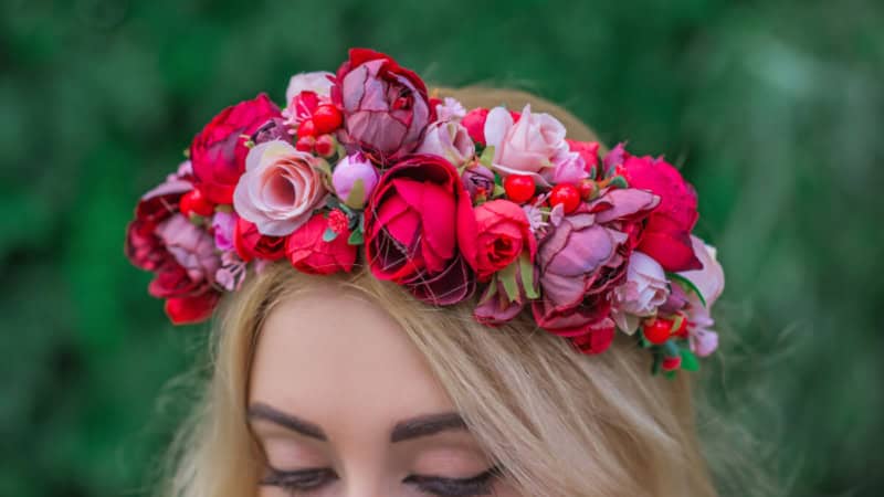 Eine Frau trägt einen Blumenkranz auf ihrem Kopf und posiert für ein Foto.