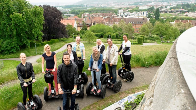 Ein Gruppenfoto von Segway-Tour-Teilnehmer, die Stadt Stuttgart im Hintergrund.