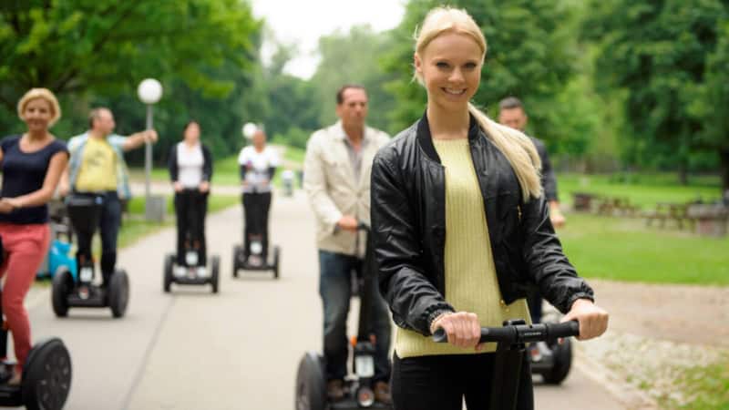 Die Segway-Tour-Teilnehmer rollen gemeinsam durch einen Park in Stuttgart.
