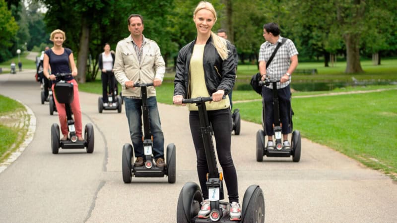 Die Teilnehmer einer Segway Tour in Stuttgart fahren durch den Park.