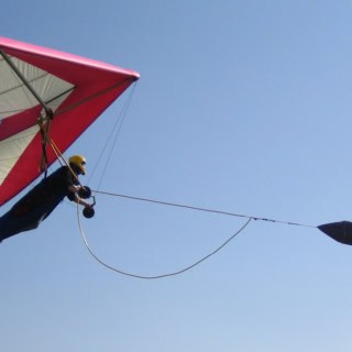 Drachenfliegen am Hiimmel. Person hängt und wird vom Seil gezogen