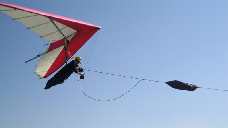 Drachenfliegen am Hiimmel. Person hängt und wird vom Seil gezogen