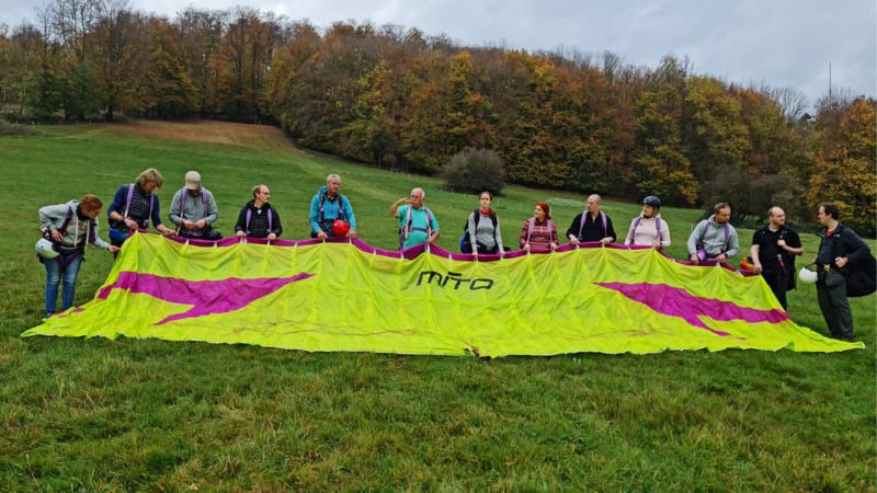 Teilnehmer des Kurses stehen vor dem Gleitschirm