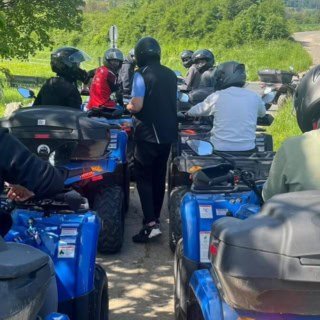 Teilnehmer einer Quad Tour fahren gemeinsam über grünes, unbefestigtes Gelände.