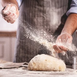 Mann knetet frischen Teig mit reichlich Mehl - Backkurs bei Frankfurt