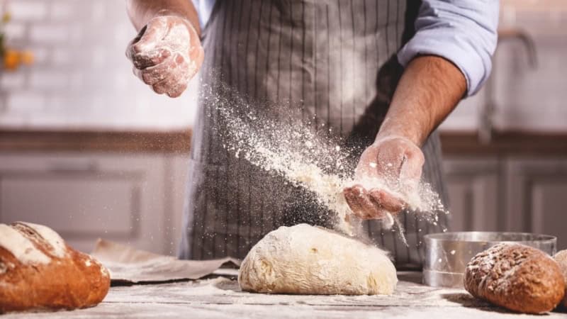 Mann knetet frischen Teig mit reichlich Mehl - Backkurs bei Frankfurt