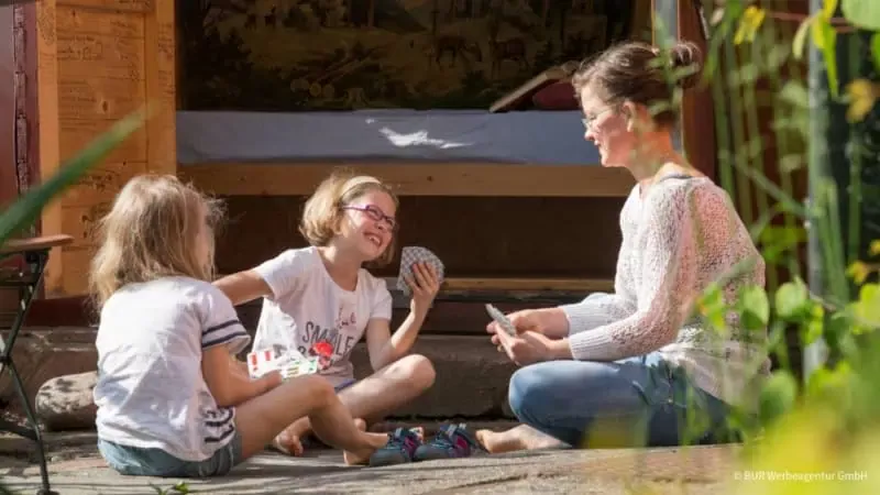 Mutter spielt Karten mit Kindern vor dem Kofferhotel