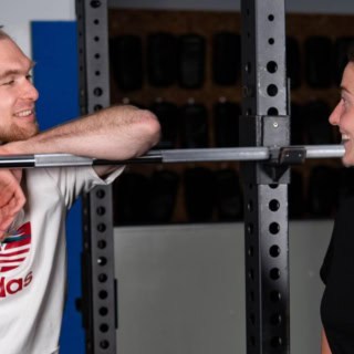 Eine Trainerin bespricht mit einem Mann im Fitnessstudio Übungen.