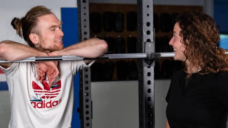 Eine Trainerin bespricht mit einem Mann im Fitnessstudio Übungen.