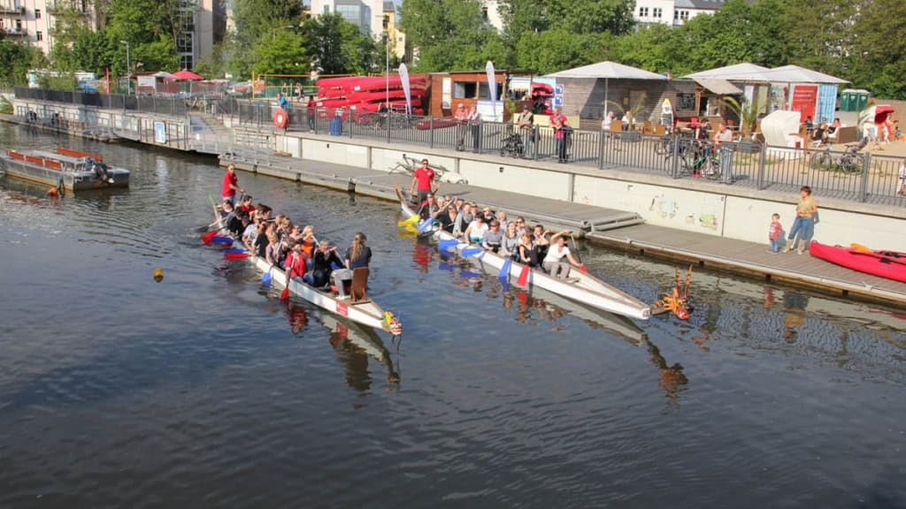 Leipzig-Drachenboot-Hafen Drachenboote an einer Anlegestelle mit Ruderern im Sonnenschein.