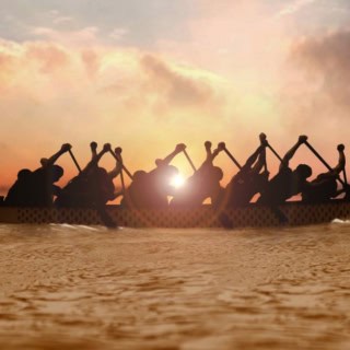 Ein Drachenboot was über eine See bei Sonnenuntergang fährt.