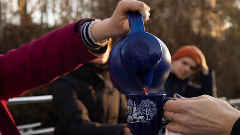 Glühwein wird dampfend heiß in eine Tasse eingeschenkt.