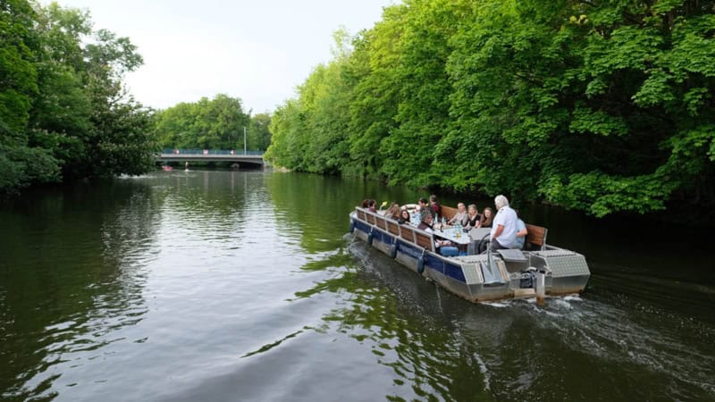 Motorboot in Fahrt auf einen Kanal umgeben von Bäumen.