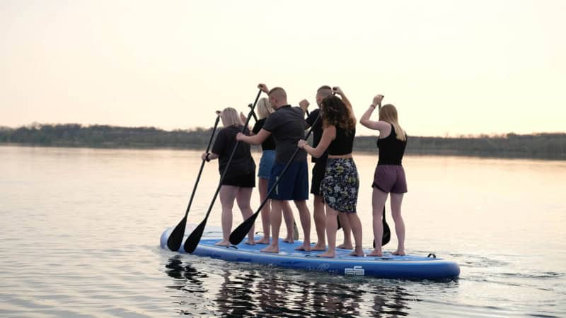eine Gruppe paddelt zusammen auf einem stand up paddle auf einem See