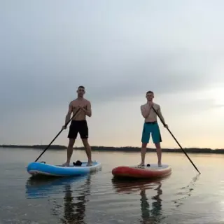 2 Männer fahren stand up paddle auf einem See, im Sonnenuntergang