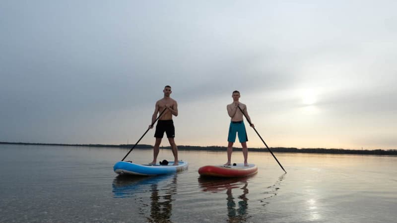 2 Männer fahren stand up paddle auf einem See, im Sonnenuntergang