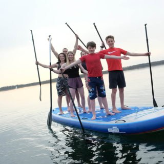 Eine Gruppe von Kindern steht auf einem XXL stand up paddle