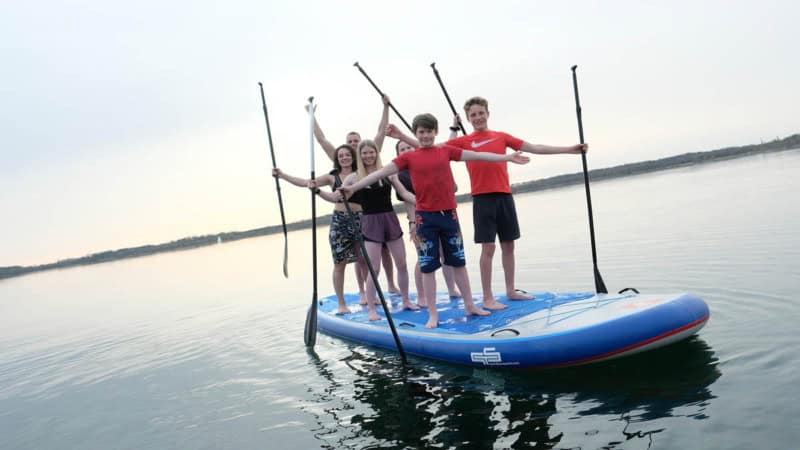 Eine Gruppe von Kindern steht auf einem XXL stand up paddle