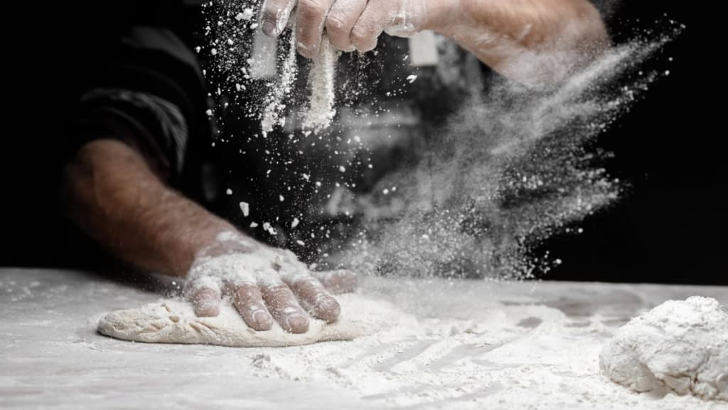 Pizza Workshop Frankfurt - Teig Ein Mann knetet mit den Händen Pizzateig auf einem Tisch - Kochkurs bei Frankfurt