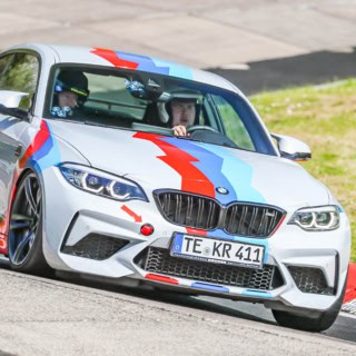 Rennfahrer fährt mit Beifahrer im BMW M2 Competition in eine Kurve - Renntaxi.