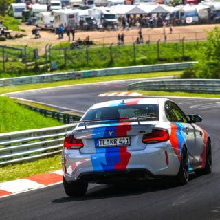 Zusehen ist das Heck des BMW M2 Competition, der die Rennstrecke entlang fährt.