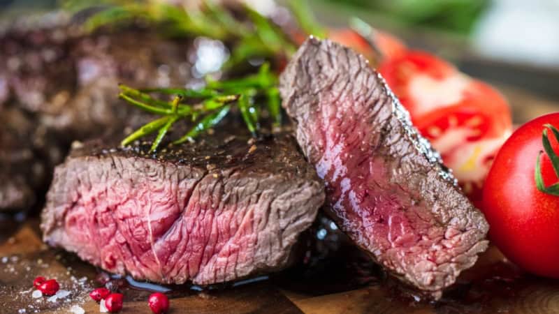 Ein aufgeschnittenes medium Steak, welches mit Gemüse angerichtet ist.