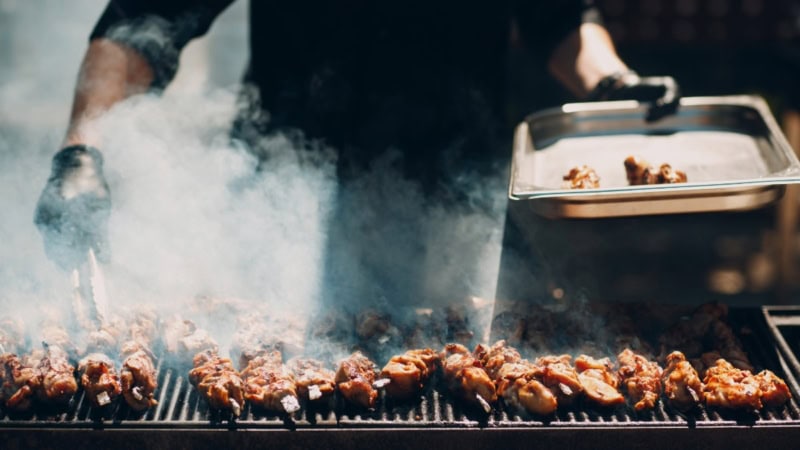 Ein Mann grillt Fleischspieße auf einem Grill.