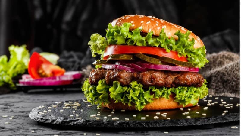 Ein saftiger frischer Burger auf einer Steinplatte serviert.