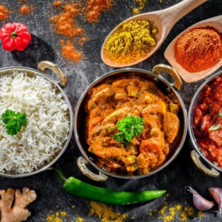 Ein rotes und ein gelbes Currygericht sind in Töpfen mit Reis aufgetischt.