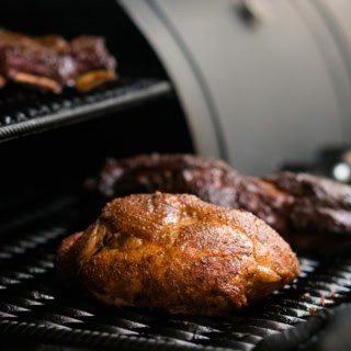 Eine Fleischplatte wird in den Smoker geschoben.