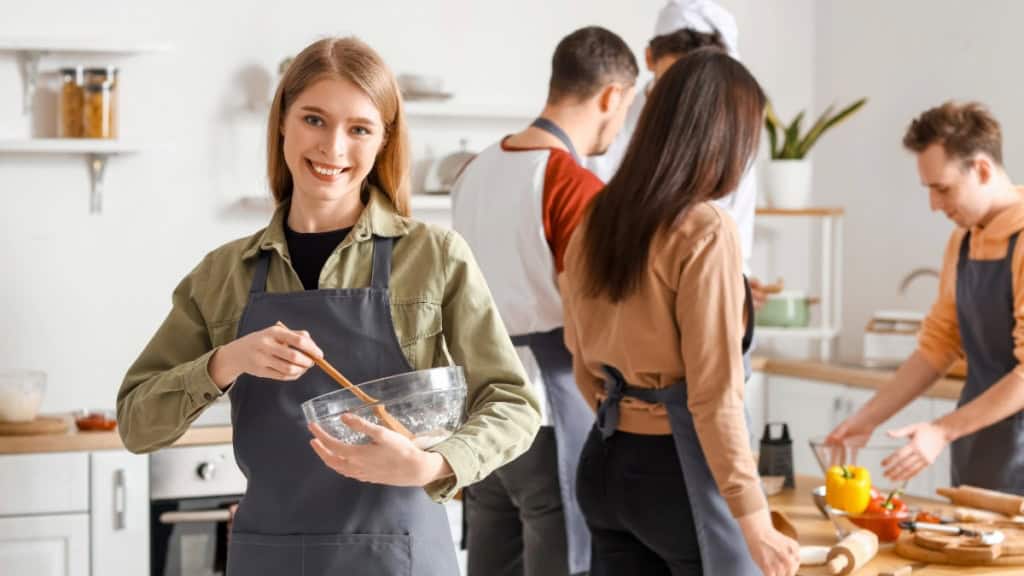 Kochkurs-soßen-kochgruppe Eine Gruppe Kochkursteilnehmer die gemeinsam ein Gericht kocht.