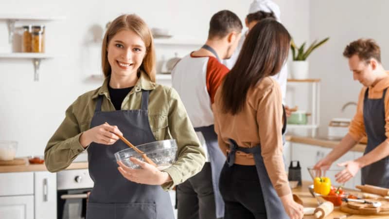 Eine Gruppe Kochkursteilnehmer die gemeinsam ein Gericht kocht.