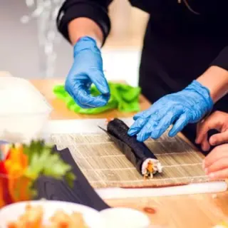 Sushi welches von Kochkursteilnehmern gerollt wird.