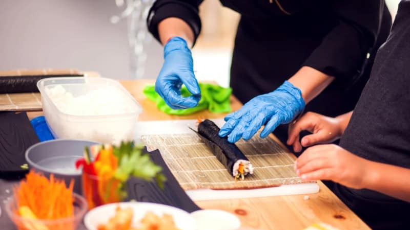 Sushi welches von Kochkursteilnehmern gerollt wird.