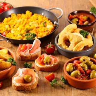 Frittierte Tintenfischringe, Ofenkartoffeln, Oliven und weitere Tapas auf einem Tisch angerichtet.