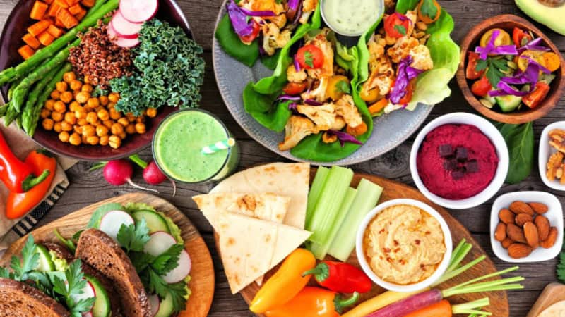 Salate, Brot und verschiedene Vegane Dips auf einem Tisch.