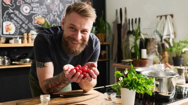 Ein Kochlehrer eines Veganen Kochkurses der lächelt.