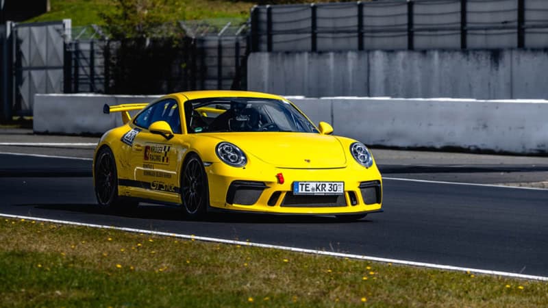 Frontale Aufnahme eines gelben Porsche GT3 MR auf einer Rennstrecke.