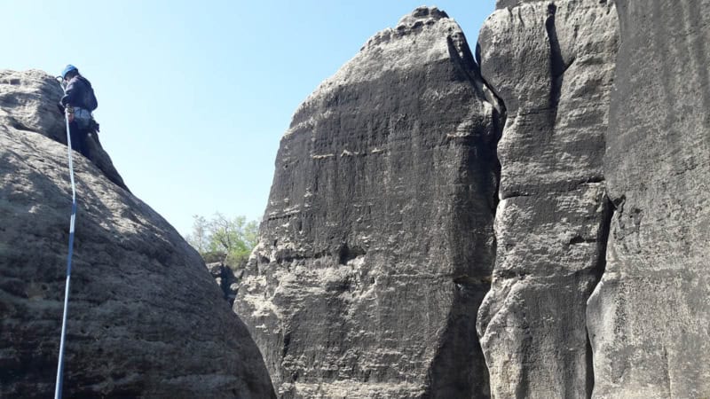 Ein Kletterer seilt sich zur Übung von einem niedrigen Sandsteinfelsen ab.