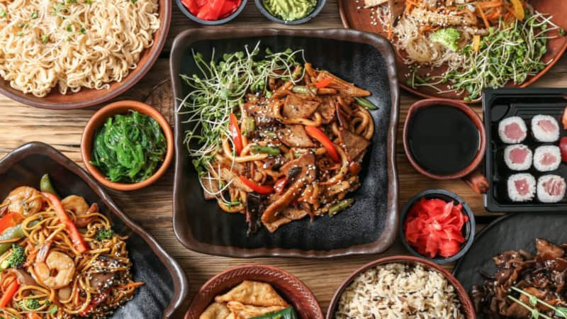 Asiatische Nudelgerichte, Algensalat, Reis und Sushi aufgetischt.