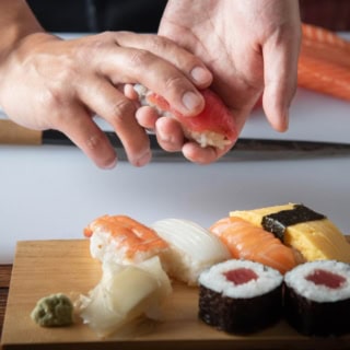 Ein Sushi Stück wird auf eine Sushi Platte gelegt.