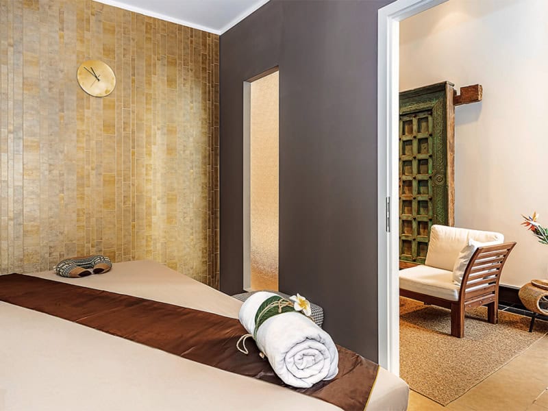 Ein zusammengerolltes Handtuch liegt auf einer Massage-Liege in einem Massage-Studio